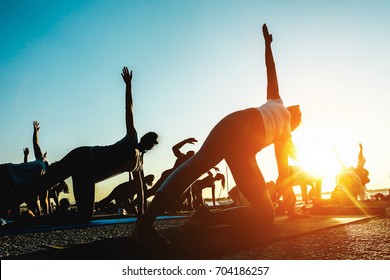 Silhouette of people doing yoga outdoor - Meditation and sport concept for healthy and relaxing lifestyle - Focus on close up woman - Powered by Shutterstock