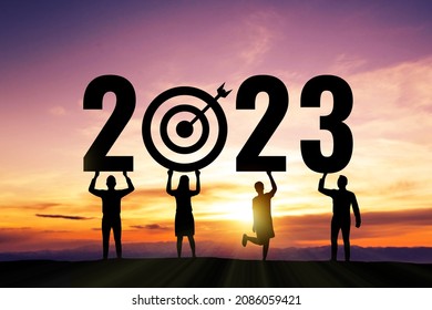 Silhouette people holding numbers 2023 with colorful dramatic sky at sunset. Concept for success in the future goal and passing time