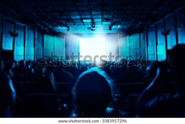暗い映画館に座っている人のシルエット 画面から青い光 ぼかした背景 の写真素材 今すぐ編集