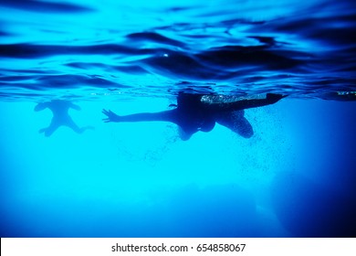 silhouette of people swim underwater. People swim and snorkel. View underwater. - Powered by Shutterstock