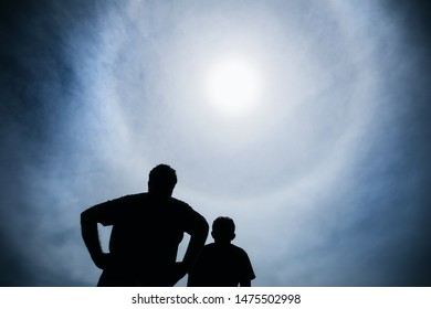 Silhouette Of People Watching A Solar Halo During A Partial Solar Eclipse