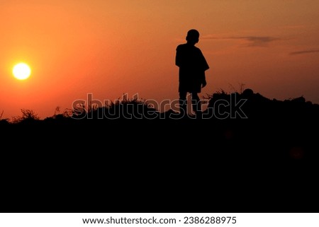 Silhouette of person against the sun sunset sunrise top of the hill intense aflame red yellow orange fire black stark difference 