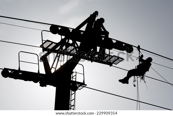 Silhouette of a
person climbing a cabin lift
pillar.