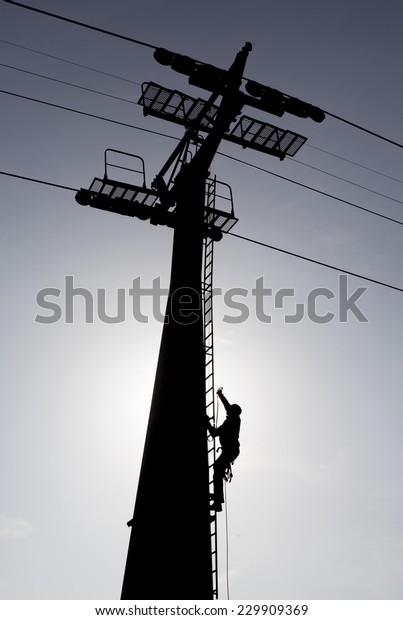 Silhouette of a\
person climbing a cabin lift\
pillar.