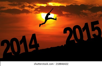 Silhouette person jumping over 2015 on the hill at sunset