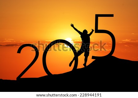 Silhouette person jumping over 2015 on the hill at sunset