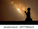 A silhouette of a person kneeling in prayer under a starry night sky with the Milky Way galaxy prominently visible in the background.