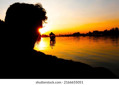 A silhouette of a person with a light star enjoying boat ride in a beautiful lake at sunset