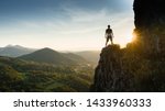 Silhouette of the person on the high rock at sunset. Satisfy hiker enjoy view. Tall man on rocky cliff watching down to landscape. Vivid and strong vignetting effect.