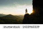 
Silhouette of the person on the high rock at sunset. Satisfy hiker enjoy view. Tall man on rocky cliff watching down to landscape. Vivid and strong vignetting effect.