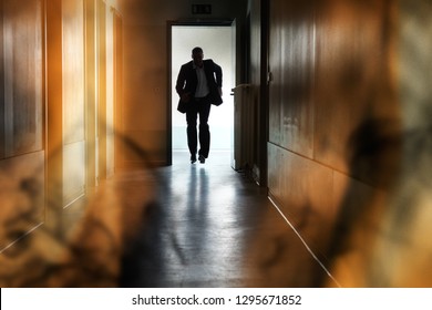 Silhouette Of Person Running Out Of Fire Escape On Corridor Of Building