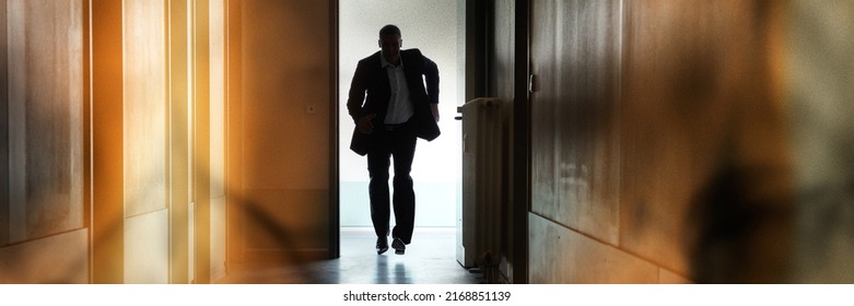 Silhouette Of Person Running Out Of Fire Escape On Corridor Of Building