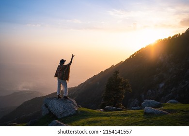 Silhouette of person stand on peak of mountain with hands raised up on sunset, Triund Trek, Himachal Pradesh, India. - Shutterstock ID 2154141557