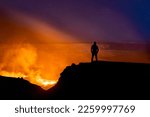 A silhouette of person watching the Kilauea volcano under beautiful starry night sky in Hawaii