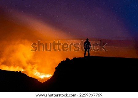 A silhouette of person watching the Kilauea volcano under beautiful starry night sky in Hawaii