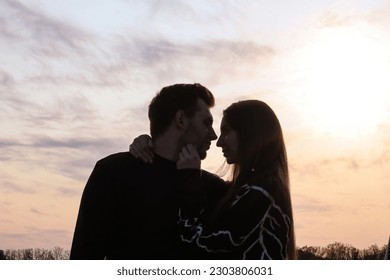 Silhouette photo of a couple in love at sunset.Portrait of a man and a woman.Photo at sunset.Silhouette portrait.Rays of the sun.Romantic photo.Backlight.Hugs of a couple in love.Sensual photo.Date.