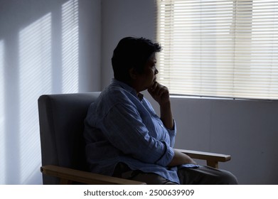 Silhouette photo of senior Asian woman feeling upset, sad, unhappy or disappoint crying lonely in her room. Elder people mental health care problem lifestyle concept. - Powered by Shutterstock