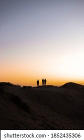 Silhouette Photo Of Three People Standing On Top Of A Mountain At Sand Dunes North Of Sydney