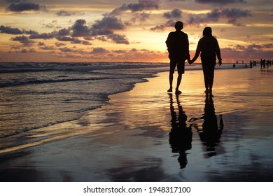 a silhouette photo walking along the beach at sunset romantically - Powered by Shutterstock