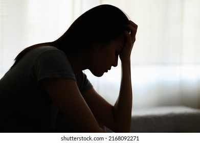 Silhouette photo of young Asian woman feeling upset, sad, unhappy or disappoint crying lonely in her room. Young people mental health care problem lifestyle concept. - Shutterstock ID 2168092271
