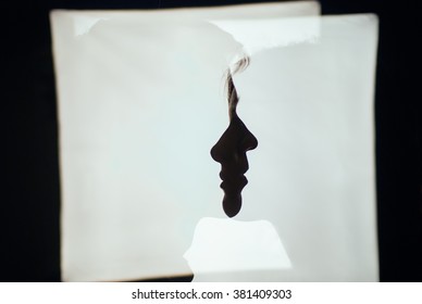 A silhouette photograph of a couple: shadows of a boy and a girl in each other on white background