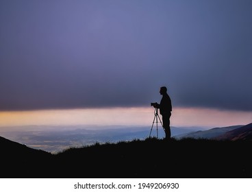 Silhouette of photographer with camera on tripod at cloudy sunset in Karkonosze Giant Mountains
