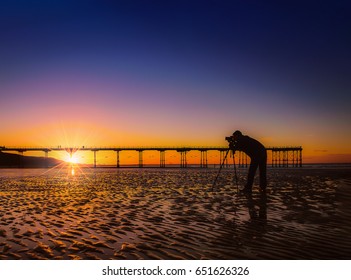 Silhouette of a photographer on beautiful sunset or sunrise at pier Saltburn by the Sea, North Yorkshire UK.