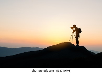 silhouette of photographer on top of mountain at sunset background
