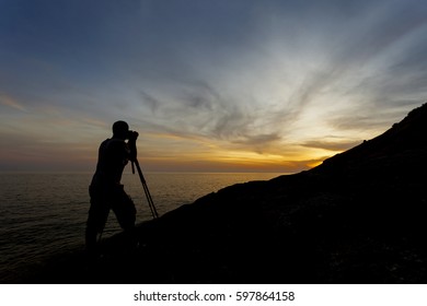 Silhouette of a photographer or traveler using a professional DSLR camera,photographer take sunset photo.