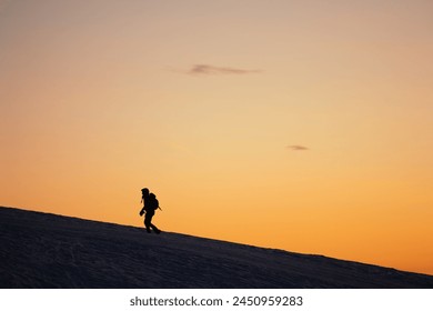 Silhouette picture of a hiker during a colorful winter sunset in the Orobie Alps, Northern Italy - Powered by Shutterstock