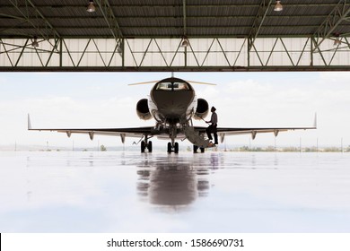 Silhouette Of Pilot Boarding Private Jet In Hangar