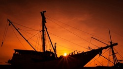 The Silhouette Of A Pinisi Boat At Red Orange Sunset Time.