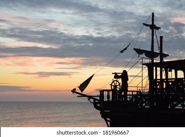 Silhouette Of A Pirate Ship With A Captain Behind Steering Wheel, Looking Through Spyglass. (not An Actual Ship, Imitation)