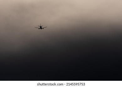 A Silhouette Of а Plane In The Sky At The Inclement Weather.