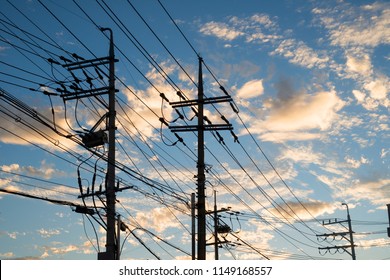Silhouette of poles and power lines in the sunset.