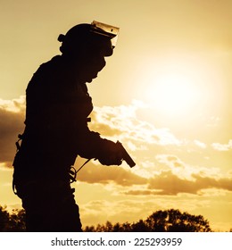 Silhouette Of Police Officer With Pistol At Sunset