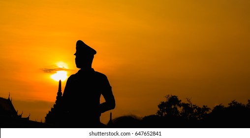 Silhouette of police standing on the sunset background.