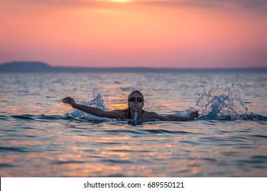 Silhouette Portrait Of Female Swimmer Swimming In Ocean At Sunset Over Sea. Water Sport And Healthy Lifestyle Concepts.