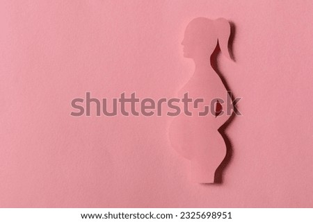 silhouette of pregnant woman on pink background, monochrome. waiting childbirth, reproductology, gynecology. happy duration of pregnancy. concept birth of child. Design cut out of paper. copy space