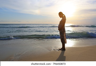 Silhouette pregnant woman standing alone on the beach at evening sunset. - Powered by Shutterstock