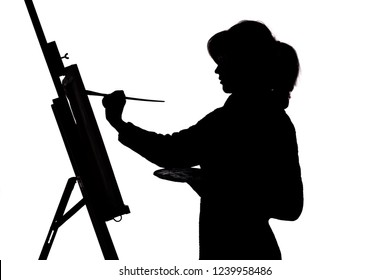 Silhouette profile of a young woman painting a picture on an easel on a white isolated background, the figure of a girl with a brush and a palette of colors , a concept of hobby and creative