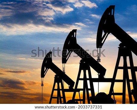 silhouette of a pumpjack with piston pump on an oil well against the background of sky