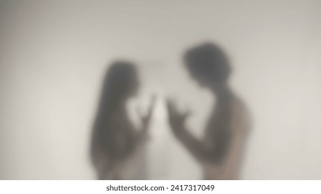 Silhouette of a quarreling couple behind a frosted glass or curtain. A woman and a man are quarreling and emotionally gesticulating with their hands. - Powered by Shutterstock