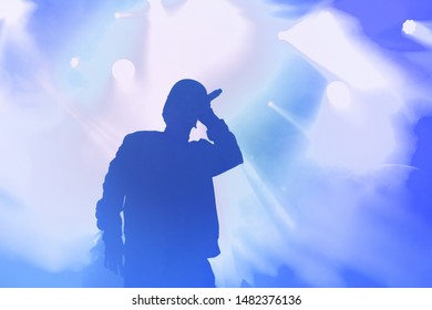 Silhouette of rap singer on concert stage. Bright blue wallpaper with hip hop artist on festival - Powered by Shutterstock