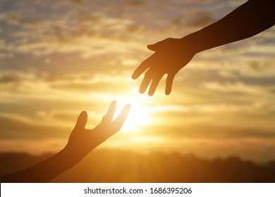 Silhouette of reaching, giving a helping hand, hope and support each other over sunset background.  - Shutterstock ID 1686395206