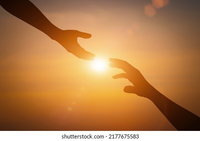 Silhouette of reaching, giving a helping hand, hope and support each other over sunset background. - Powered by Shutterstock