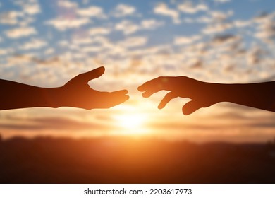 Silhouette of reaching, giving a helping hand, hope and support each other over sunset background. Help, friendship international day concept. - Powered by Shutterstock