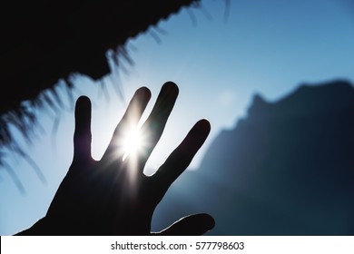 Silhouette Reaching Up To The Sky Against Bright Sunlight With Rays