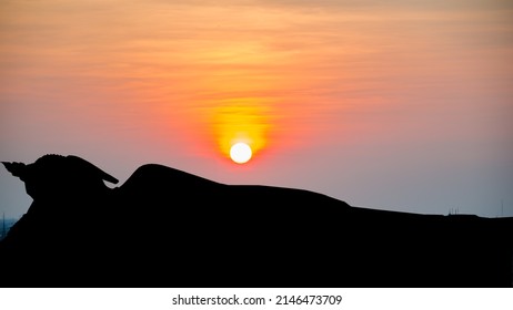 Silhouette reclining buddha on sunset background.