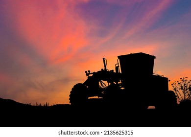 Silhouette of Road grader tractor with clipping path working at construction site sunset sky background